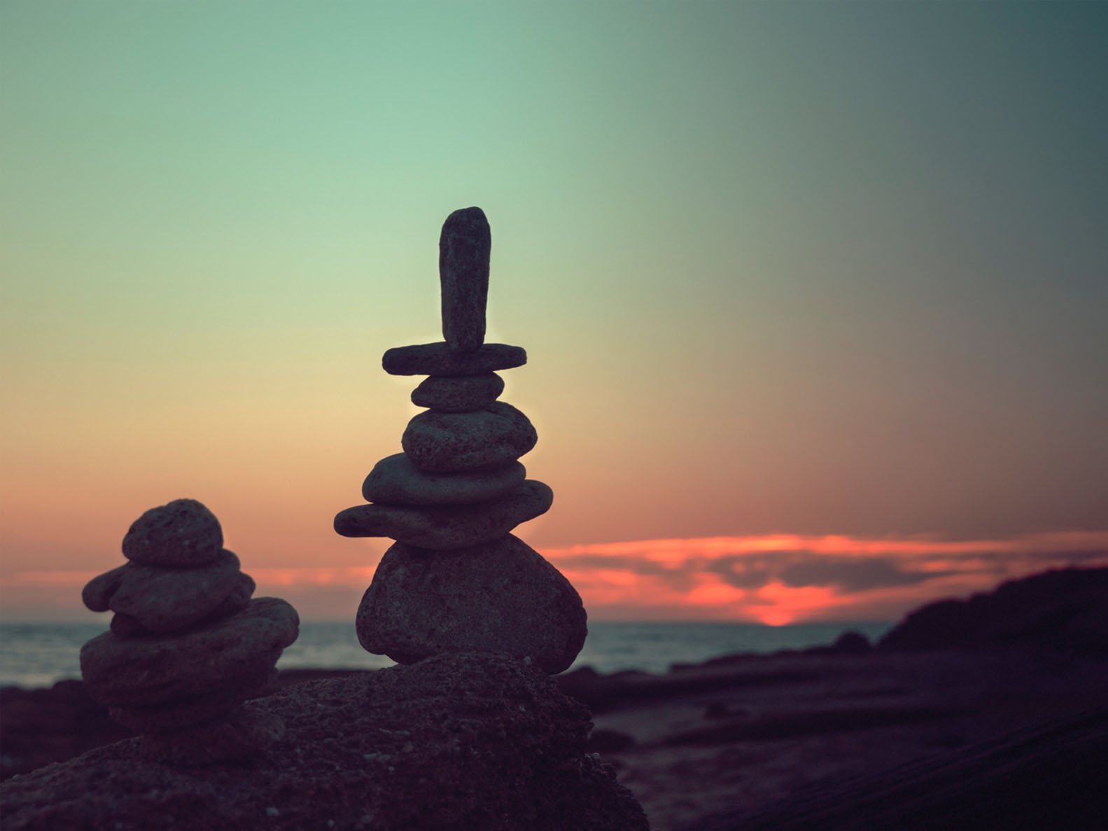 stones stacked and balancing in front of sunset